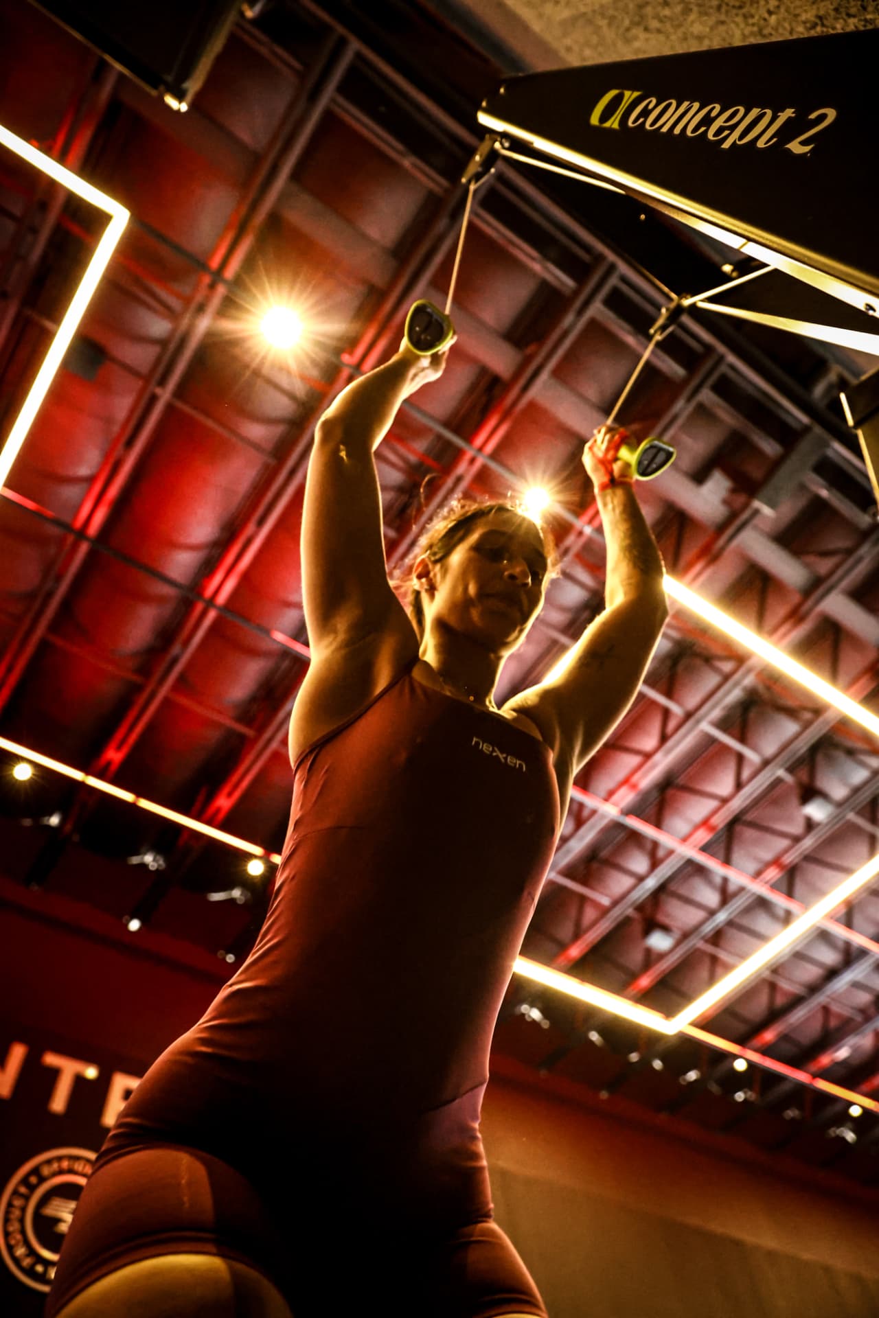 Atleta no remô Concept 2 sob as luzes da arena